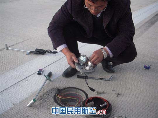 图为工作人员检查嵌入式跑道灯并测试螺栓扭矩